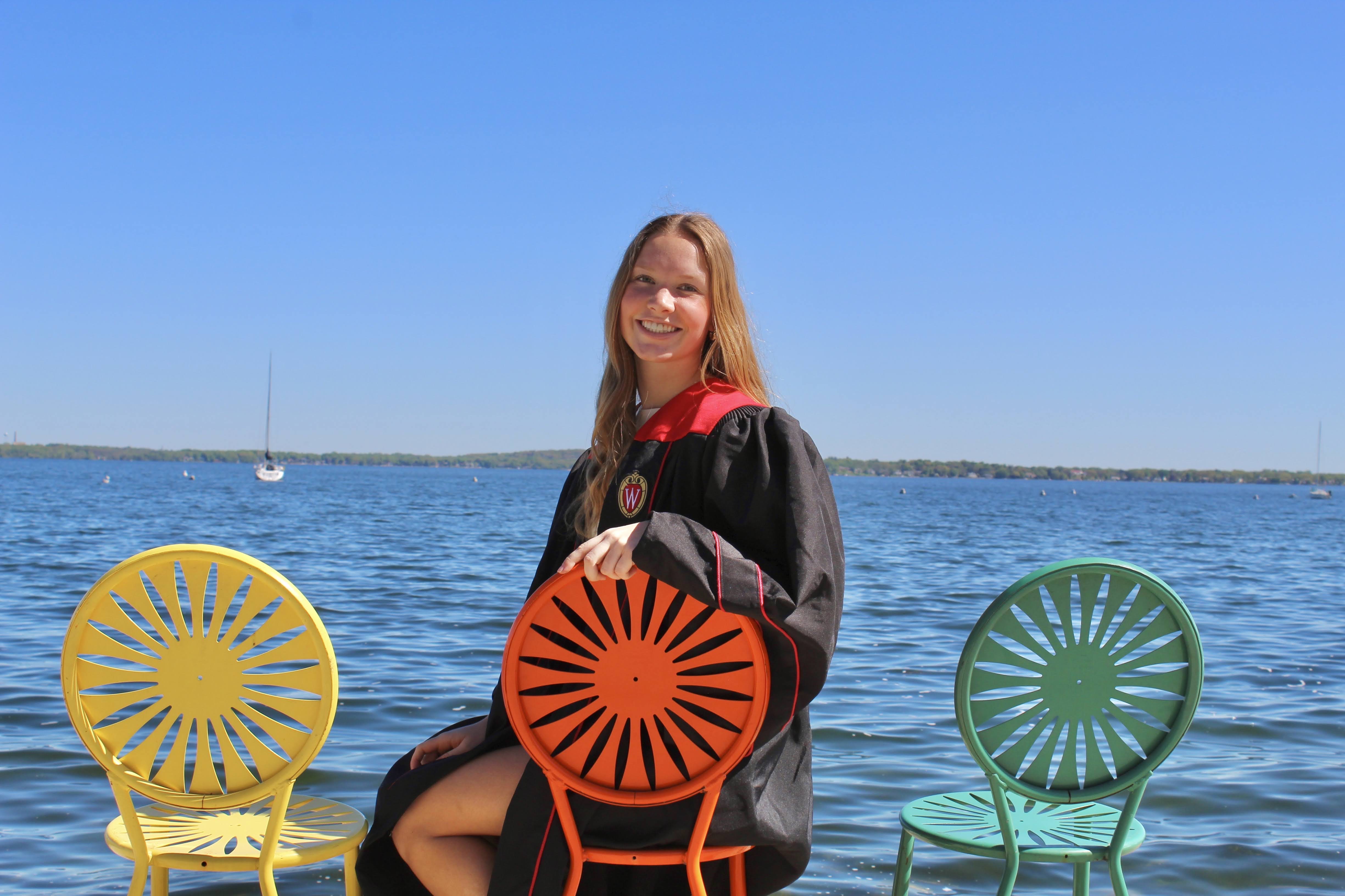 Claire sitting on the Terrace Chairs alongside Lake Mendota ahead of her gradution.